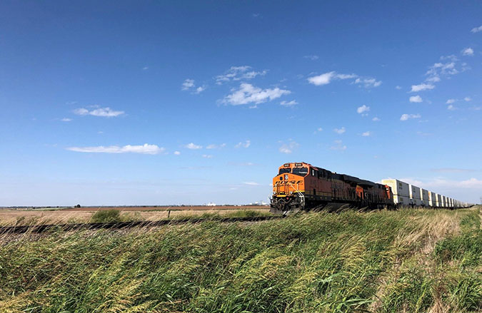 An intermodal train passing through billowing grass in Enid, Oklahoma